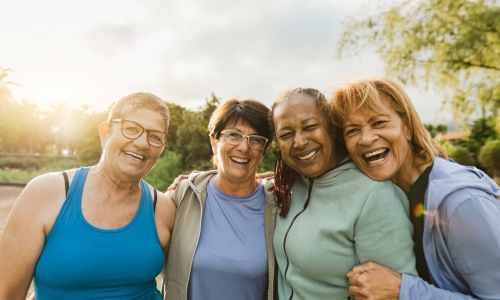 a group of 4 woman smiling and laughing together while enjoying the outdoors