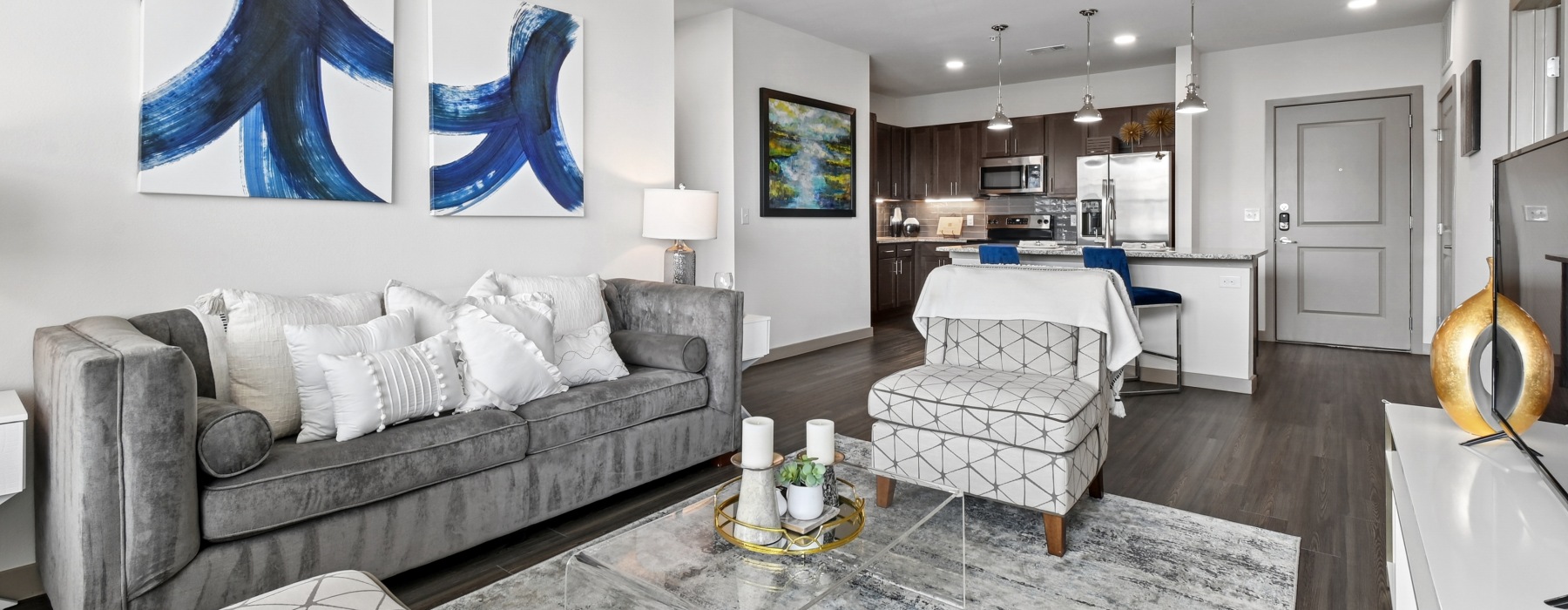 Model living room at our senior living apartments in Plano, TX, featuring wood grain floor paneling and couches.
